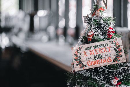 A charming wooden plank sign featuring a classic Christmas carol lyric, "Have Yourself a Merry Little Christmas," decorating a faux Christmas tree with tiny Santa figurines and bells, conveying a vintage holiday feelの写真素材
