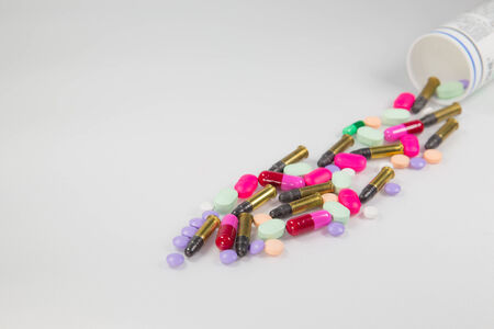 Colorful pills and bullet  on white background