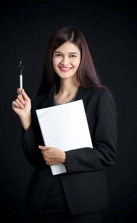 Portrait of young asian businesswoman with document  on black background.の写真素材