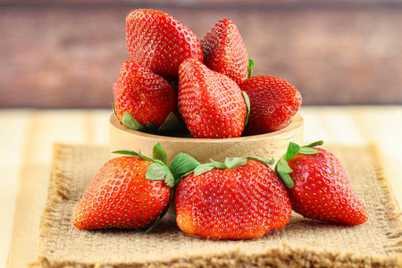 Fresh strawberries in a bowl on wooden table with low key scene.の写真素材