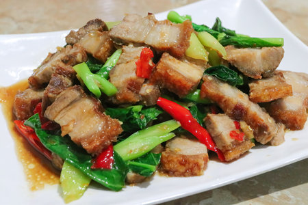 Crispy Pork Belly Stir Fry With Chinese Kale in white plateの写真素材