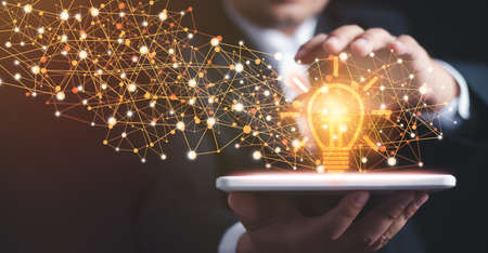 Innovative technology in science and communication concept. Abstract. Innovation. Hands holding tablet with light bulb future technologies and network connection on virtual interface background.の写真素材