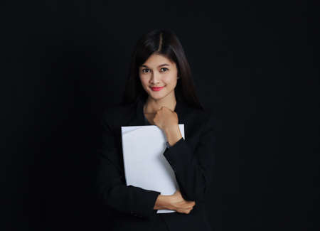 Portrait of young asian businesswoman with document  on black background, Beautiful thai girl, black jacket.の写真素材