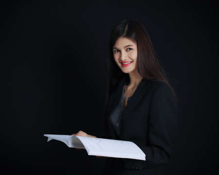 Portrait of young asian businesswoman with document  on black background, Beautiful thai girl, black jacket.の写真素材