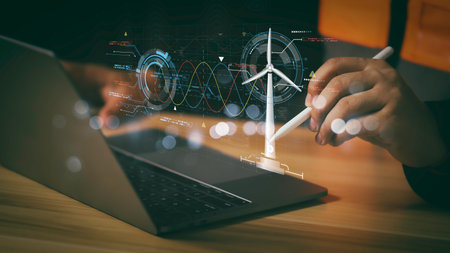 Engineer using digital tablet to analyze renewable energy data with wind turbine model and futuristic interface, representing smart technology innovation in sustainable power solutions.の写真素材