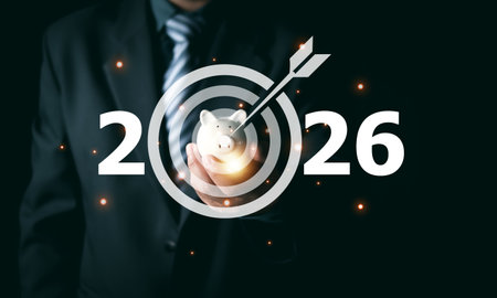 Businessman holding piggy bank with 2026 target icon. Concept of financial goal setting, saving money for future, investment strategy success, and corporate wealth management planning.の写真素材