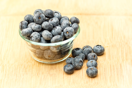 blueberries in glass bowl on cutting board.の写真素材