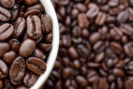 Roasted coffee beans in a white cup placed to the far left.の写真素材
