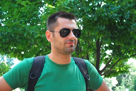 young man wearing sunglasses smiling in nature の写真素材