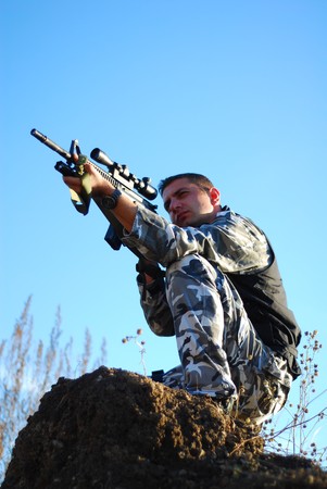 Soldier in camouflage aiming with his rifle outdoorの写真素材