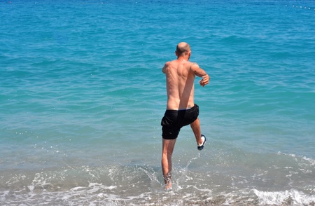 young man running toward the mediterranean seaの写真素材