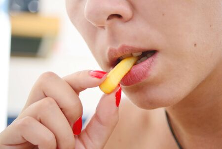 young woman eating french fries close detailの写真素材