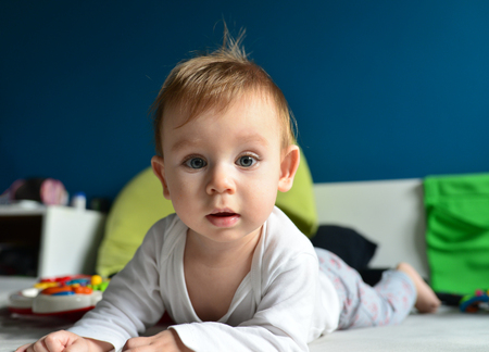 beautiful blue eyed baby kid crawling in bedの写真素材