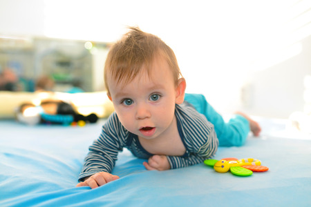 beautiful blue eyed baby kid crawling in bedの写真素材