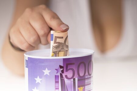 girl with large breasts put a banknote in the piggy bank