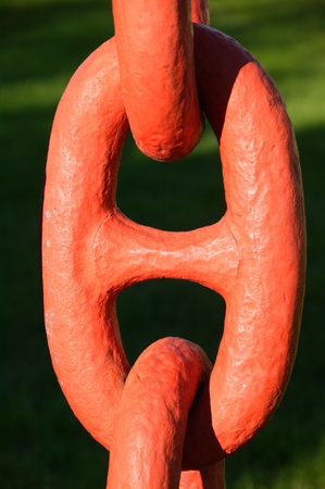 A close-up orange link from a large nautical iron anchor chain under stressの写真素材
