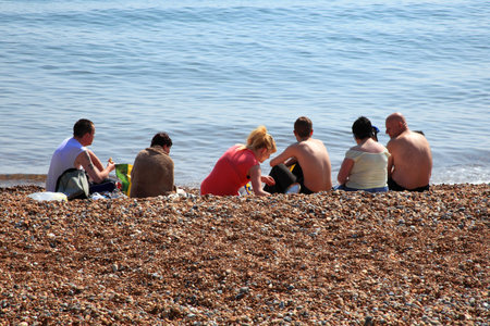 Hastings,United Kingdom, Apr 28, 2011 : A group of holidaymakers sunbathing on a pebbled beach  in Hastings in East Sussexのeditorial素材