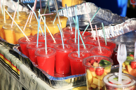 tin foil trays full of strawberry and banana smoothies in plastic glasses with straws insertedのeditorial素材