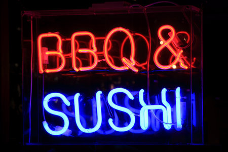 neon sign at night advertising sushi and barbecue mealsのeditorial素材