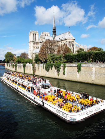 Paris, France  September 18, 2011: Tourist enjoying a tour of the River Seine passing Notre Dame cathedral aboard a Bateaux Mouches boatのeditorial素材