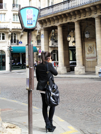Paris, France, September 18, 2011: A young woman standing at a bus stop using a mobile phone in the Rue De Richelieuのeditorial素材