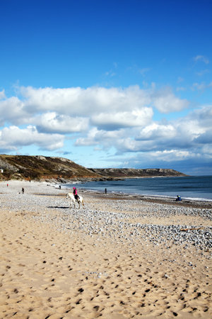Port Eynon Bay, West Glamorgan,Wales, UK, March 5, 2016 : Holidaymakers on vacation making the most of the sun on a golden sandy beach of the Gower Peninsularのeditorial素材