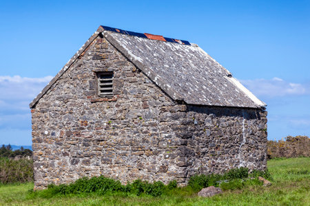 Stone barn shed in a summer pasture field on Caldey Island of the coast of Tenby Pembrokeshire South Wales, stock photo imageの写真素材