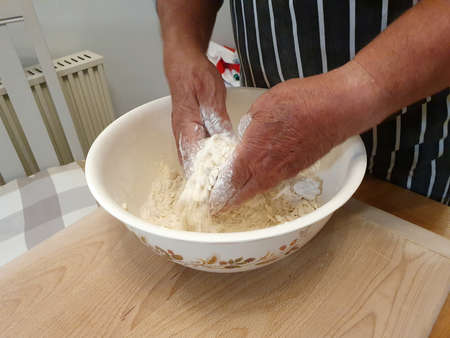 Chef mixing pastry dough by hand in a bowl, stock photo image