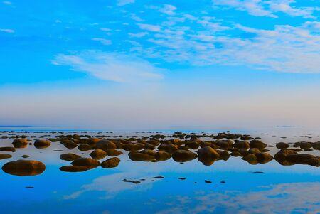 Reflections of white clouds on a blue smooth seaの写真素材