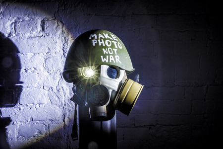 art picture of a military gas mask on a white brick wall with shadows with flash with the inscription make photo not war on Fatherland defender dayの写真素材