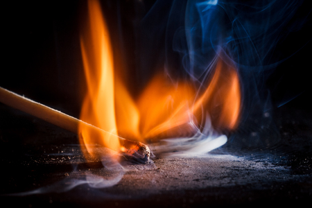 Macro shooting of a burning match with a flame of fire and smoke on a black backgroundの写真素材