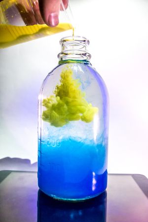 art shot of a transparent vase with a plant with clear water and blue ink in the Studio with lightingの写真素材
