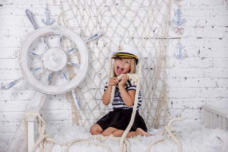 Portrait of one cute and mischievous european girl in a sea style studio on a white brick wall backgroundの写真素材