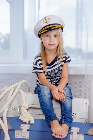 Portrait of one cute and mischievous european girl in a sea style studio on a white brick wall backgroundの写真素材