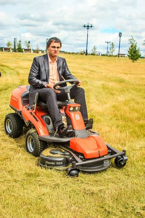 RUSSIA, YAROSLAVL -  19 JULY. 2012: The bride and groom run away from the master of ceremonies on a lawn mower across the field on a sunny day.のeditorial素材