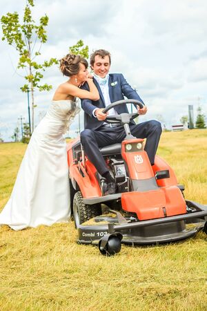 RUSSIA, YAROSLAVL -  19 JULY. 2012: The bride and groom run away from the master of ceremonies on a lawn mower across the field on a sunny day.のeditorial素材