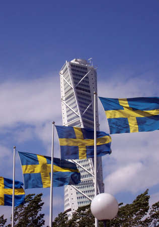 a view of the turning torso twisted tower block in malmo behind a row of swedish flagsの写真素材