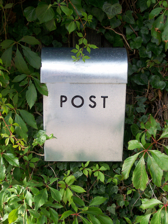 a metal postal box against a background of a hedgeの写真素材