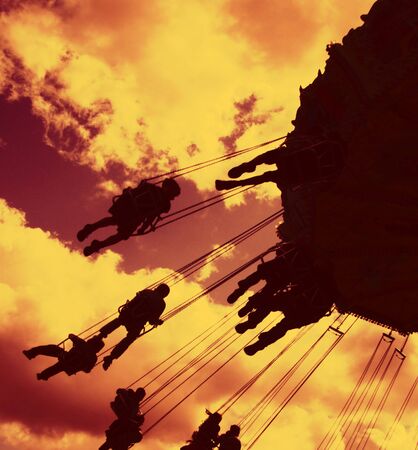 fairground rides silhouetted against a filtered evening skyの写真素材