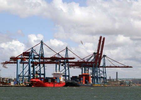 cargo ships being loaded and unloaded with containers in Gothenburg harbour by huge industrial cranesの写真素材