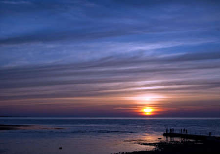 A group of people gather to watch a spectacular sunset at Torekov in Sweden.の写真素材