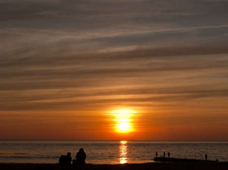 A group of people gather to watch a spectacular sunset at Torekov in Sweden.の写真素材