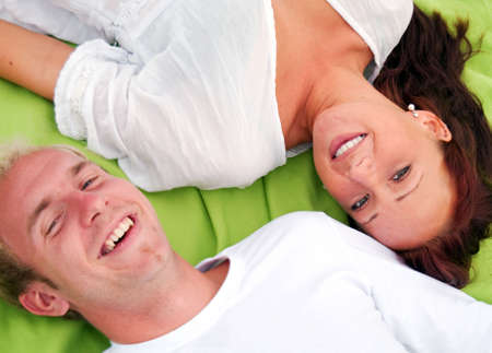 A young cute couple lie down beside each other on a picnic blanket.の写真素材
