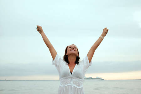 A beautiful, fit and healthy young woman throws her hands in the air in a fit of joy.