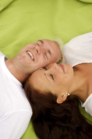 A young cute couple lie down beside each other on a picnic blanket and take a nap.の写真素材