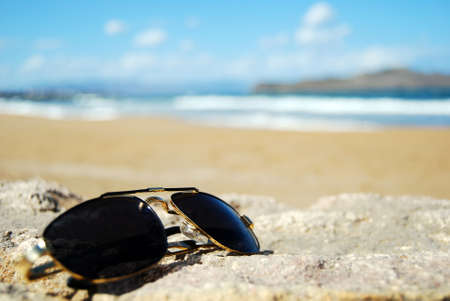 A pair of trendy sunglasses lying on an exotic beach location.の写真素材