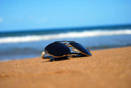 A pair of trendy sunglasses lying on an exotic beach location.