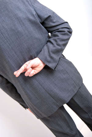 A conceptial image of a business man with his fingers crossed behind his back.の写真素材