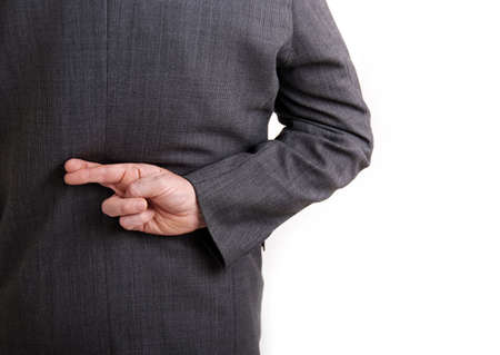 A conceptial image of a business man with his fingers crossed behind his back.の写真素材