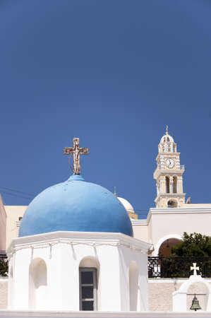A typical blue domed church in the town of fira on the greek island of santorini. The catholic cathedral can also be seen in the backgroundの写真素材